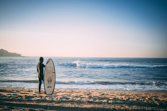 naked person holding surfboard on beach shore