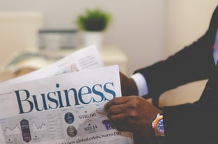 person wearing suit reading business newspaper