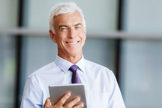 Businessman standing with tablet smiling at camera