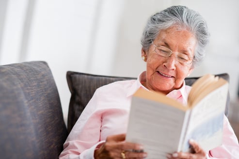 Elder woman reading a book at home and smiling-1