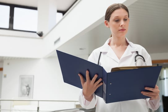 Female doctor reading folder in hospital corridor