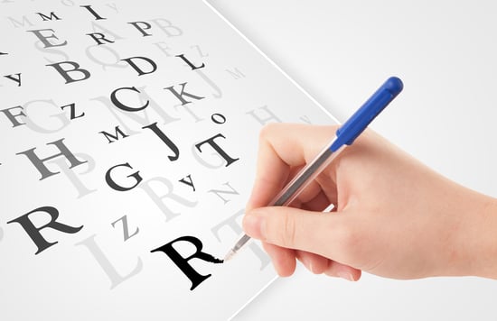 Human hand writing various letters on white plain paper