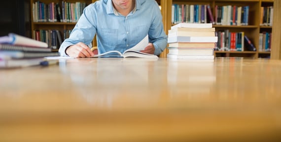 Mid section of a mature male student studying at desk in the library