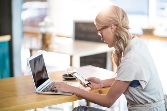 Woman using a laptop and mobile phone in cafx92xA9-1