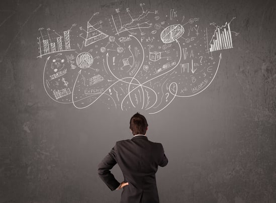 Young business man looking at sketches of graphs and symbols on the wall