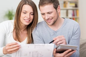Young couple planning a new purchase sitting together pointing to a document held by the wife as the husband does the necessary calculations on a calculator-Feb-14-2025-05-07-08-5495-PM